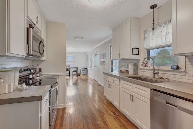 kitchen featuring stainless steel appliances, hanging light fixtures, sink, and white cabinets