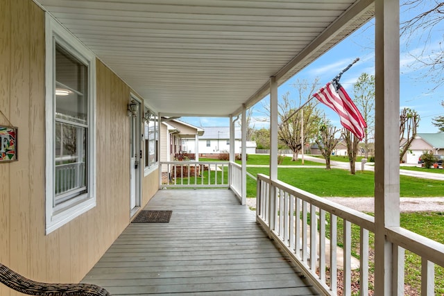 wooden terrace featuring covered porch and a lawn