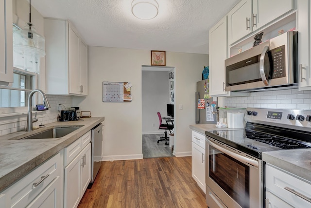 kitchen with stainless steel appliances, sink, white cabinets, a textured ceiling, and dark hardwood / wood-style flooring