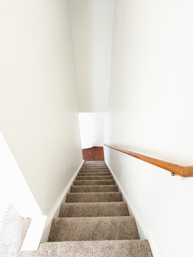 staircase featuring dark carpet