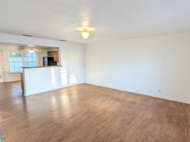 unfurnished living room featuring ceiling fan and dark hardwood / wood-style floors