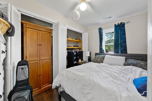 bedroom featuring dark hardwood / wood-style floors, ceiling fan, a textured ceiling, and a closet