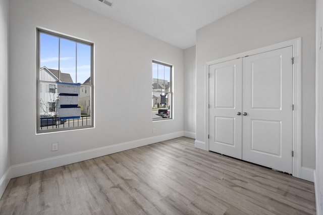 unfurnished bedroom with light wood-type flooring and a closet