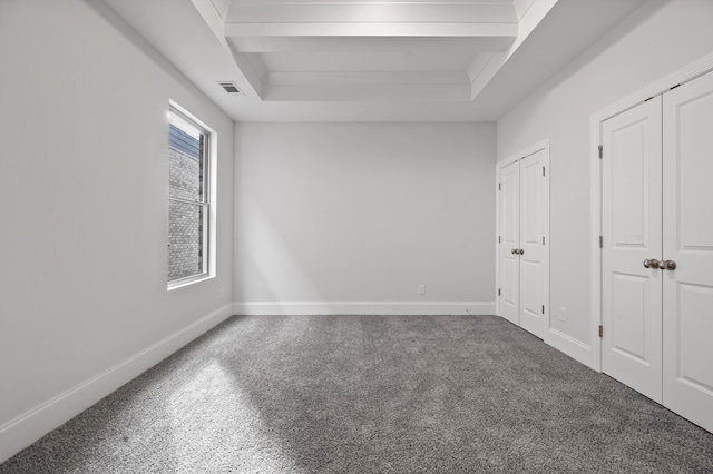 unfurnished bedroom with carpet floors and a tray ceiling