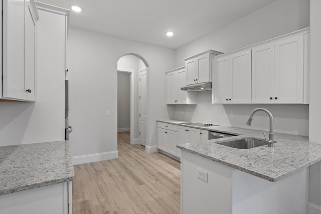 kitchen featuring white cabinets, light stone counters, and sink