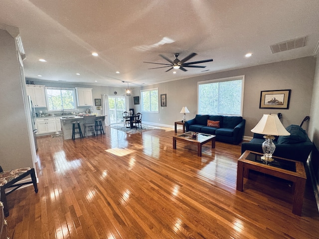 living room featuring wood-type flooring, a textured ceiling, ceiling fan, and sink