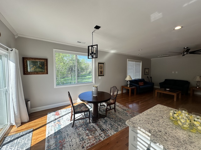 dining room featuring crown molding, dark wood-type flooring, and ceiling fan with notable chandelier