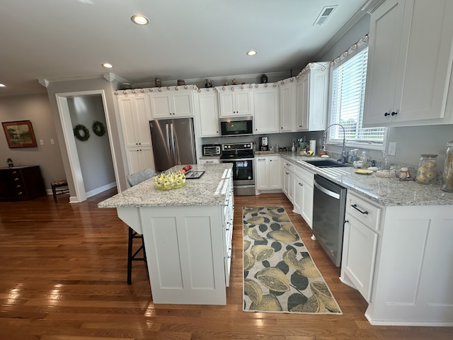 kitchen featuring light stone countertops, sink, a center island, stainless steel appliances, and white cabinets