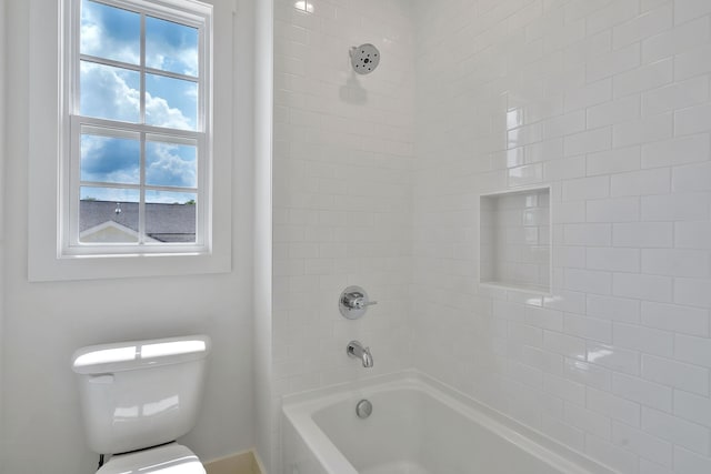 bathroom featuring tiled shower / bath combo, toilet, and a wealth of natural light