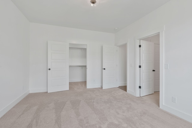 unfurnished bedroom with a closet, a spacious closet, and light carpet