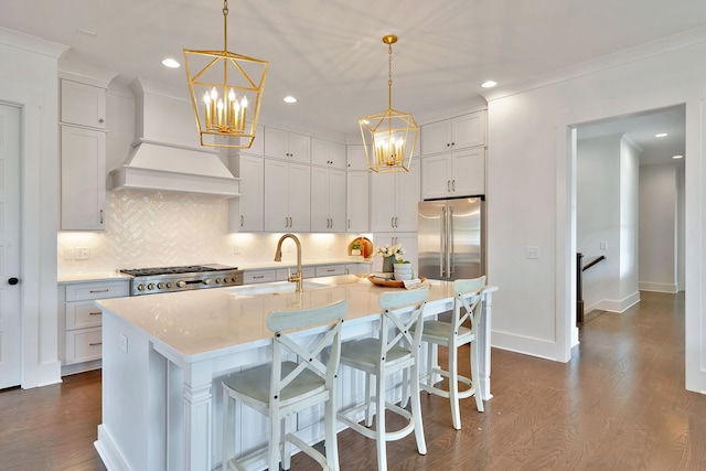 kitchen featuring custom exhaust hood, pendant lighting, high end fridge, dark hardwood / wood-style floors, and a kitchen island with sink