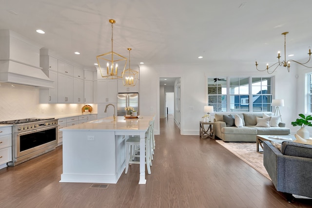 kitchen with a kitchen breakfast bar, high end appliances, white cabinets, dark wood-type flooring, and custom range hood