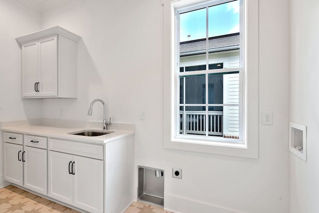 clothes washing area with electric dryer hookup, sink, light tile floors, and cabinets