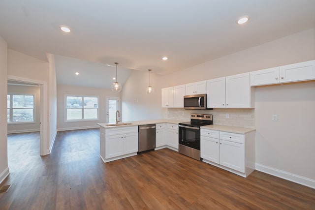 kitchen featuring stainless steel appliances, white cabinets, decorative light fixtures, vaulted ceiling, and kitchen peninsula