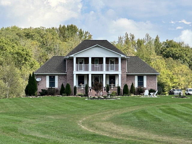 rear view of house with a lawn and a balcony