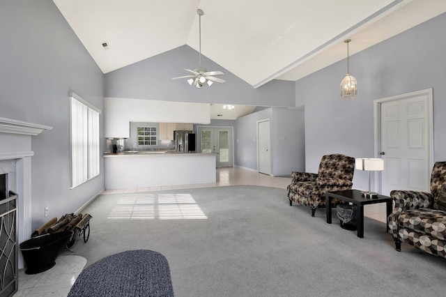 living room featuring high vaulted ceiling, a fireplace, ceiling fan with notable chandelier, and light carpet