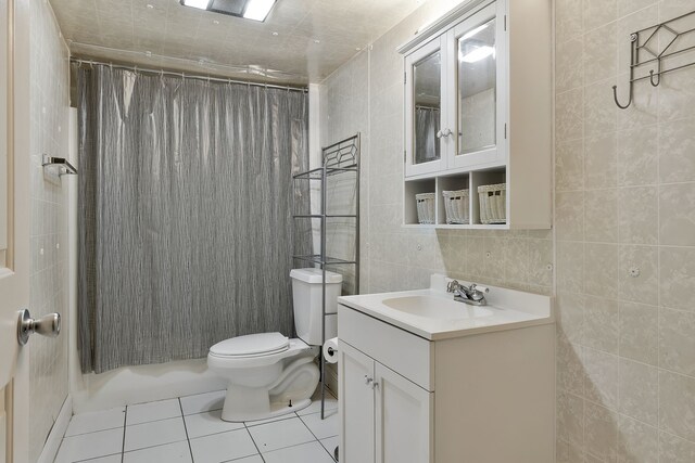 full bathroom with toilet, tile walls, tile patterned floors, shower / bathtub combination with curtain, and vanity