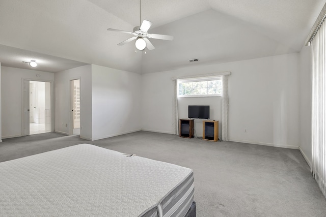 bedroom featuring ceiling fan, connected bathroom, lofted ceiling, and light carpet