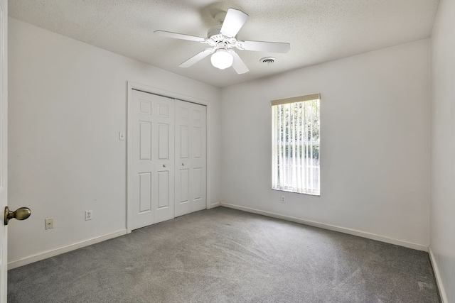 unfurnished bedroom with a textured ceiling, carpet flooring, a closet, and ceiling fan