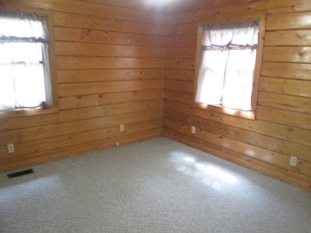 carpeted empty room featuring wooden walls