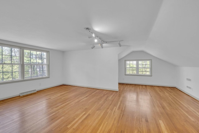 additional living space with light hardwood / wood-style flooring and vaulted ceiling