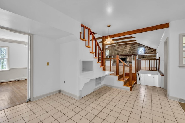 stairs with brick wall, a fireplace, lofted ceiling with beams, and hardwood / wood-style floors