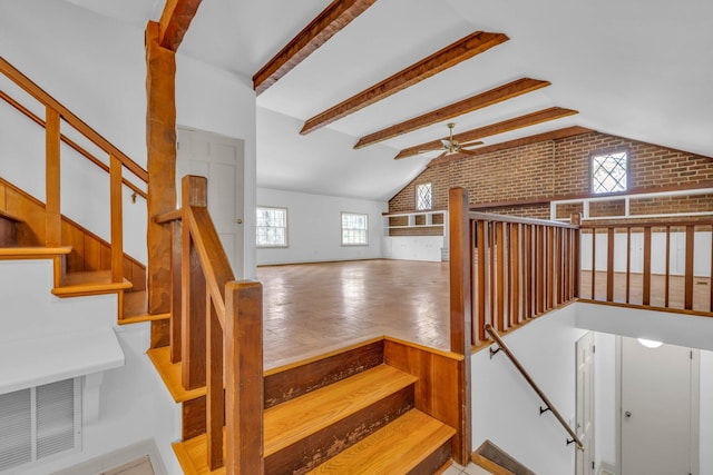 stairway with beam ceiling, ceiling fan, and brick wall