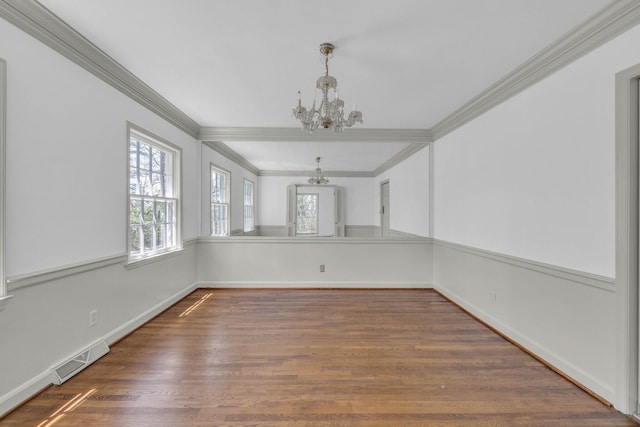 unfurnished dining area with an inviting chandelier, ornamental molding, and dark hardwood / wood-style floors