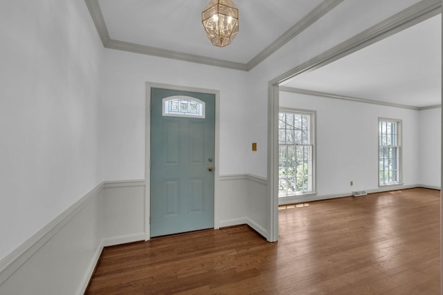 foyer featuring a chandelier, dark wood-type flooring, and crown molding