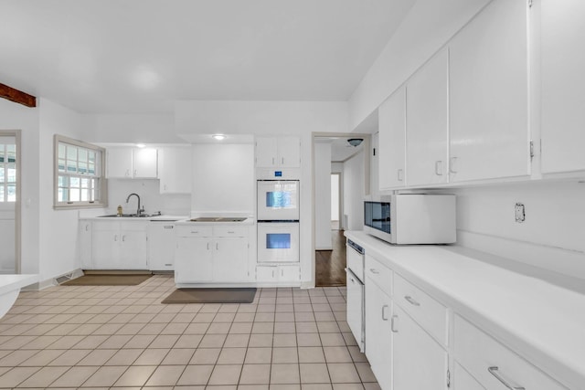 kitchen featuring white cabinets, light tile patterned flooring, sink, and white appliances