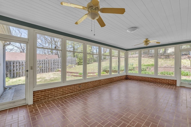 unfurnished sunroom featuring ceiling fan and a healthy amount of sunlight