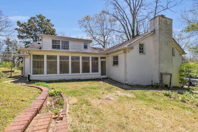 rear view of property featuring a sunroom and a yard