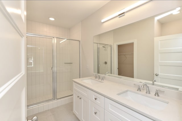 bathroom with a shower with door, vanity, and tile patterned flooring