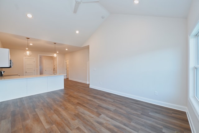 unfurnished living room featuring ceiling fan, sink, dark hardwood / wood-style flooring, and high vaulted ceiling