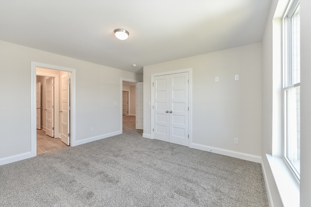 unfurnished bedroom with light colored carpet and a closet