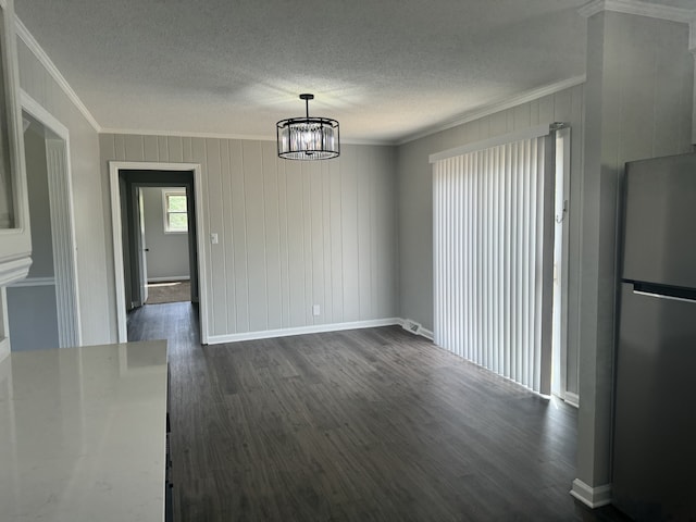 unfurnished dining area featuring ornamental molding, dark hardwood / wood-style flooring, a chandelier, and a textured ceiling