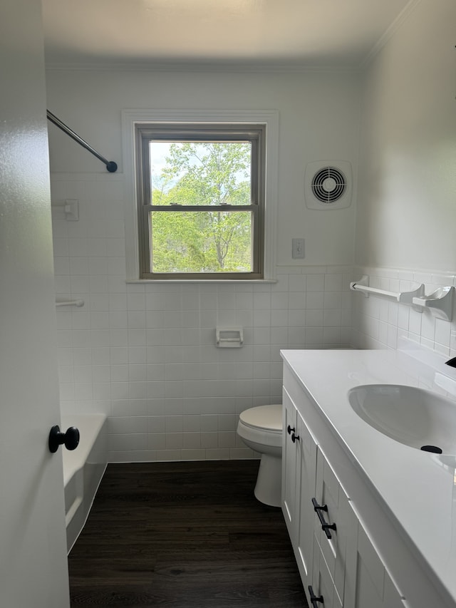 full bathroom with tile walls, hardwood / wood-style floors, toilet, vanity, and bathing tub / shower combination