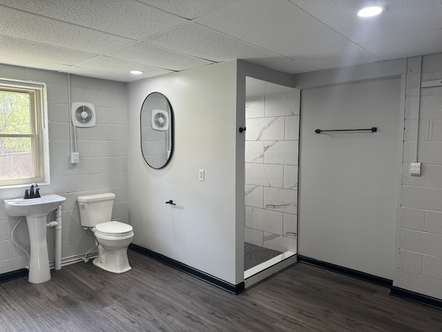 bathroom with tile walls, a drop ceiling, a tile shower, toilet, and hardwood / wood-style floors