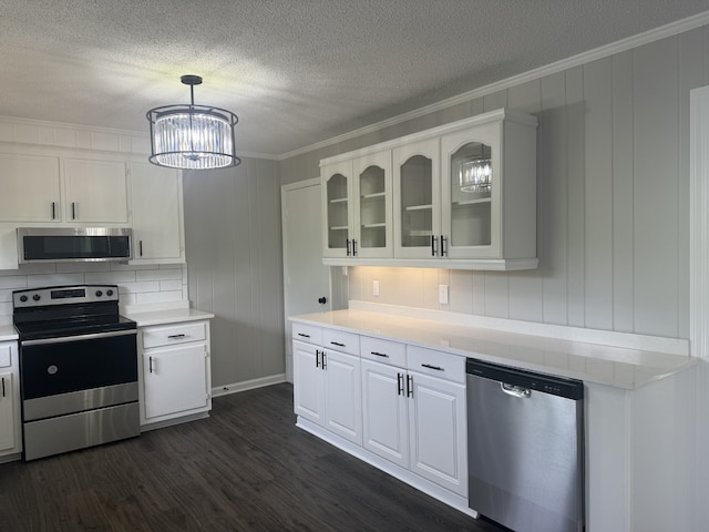 kitchen featuring appliances with stainless steel finishes, hanging light fixtures, dark hardwood / wood-style floors, white cabinetry, and an inviting chandelier