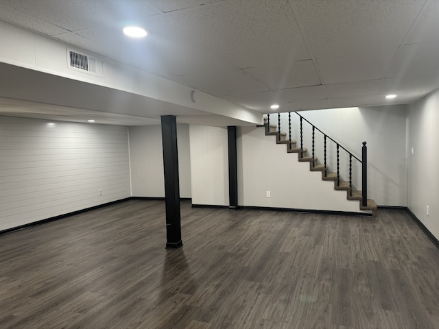 basement featuring dark hardwood / wood-style flooring and a paneled ceiling