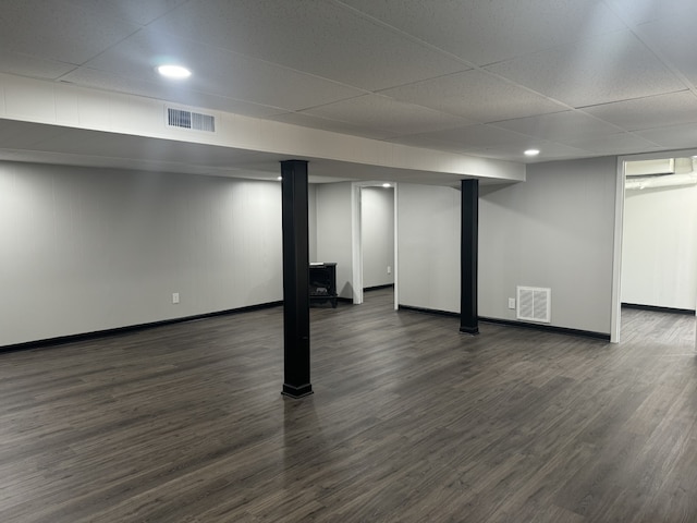 basement with a drop ceiling and dark hardwood / wood-style flooring