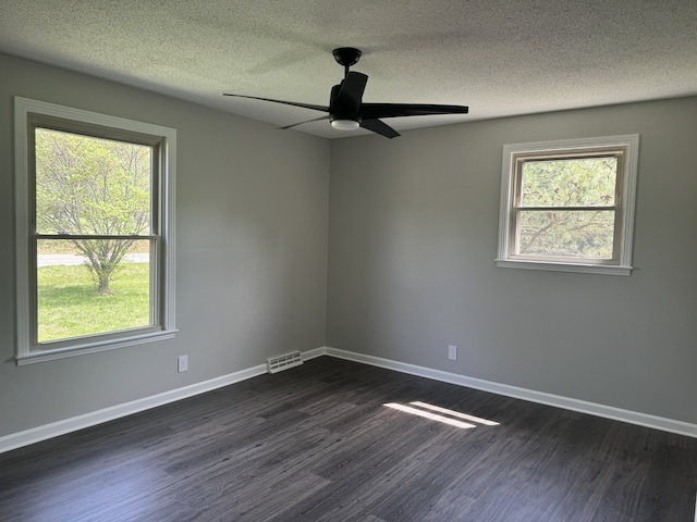 empty room featuring dark hardwood / wood-style flooring, ceiling fan, a healthy amount of sunlight, and a textured ceiling