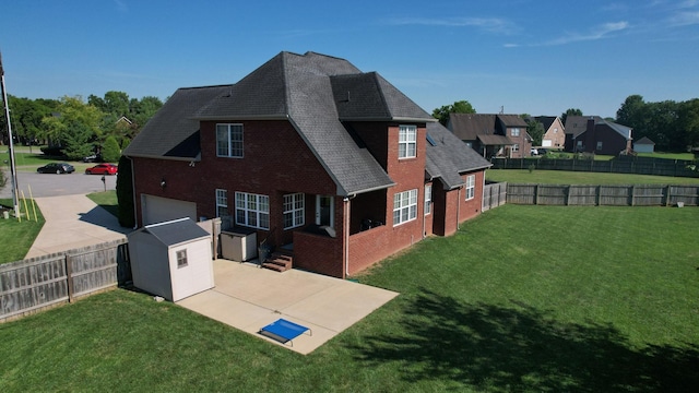 back of house with a yard, a patio area, a garage, and a storage unit