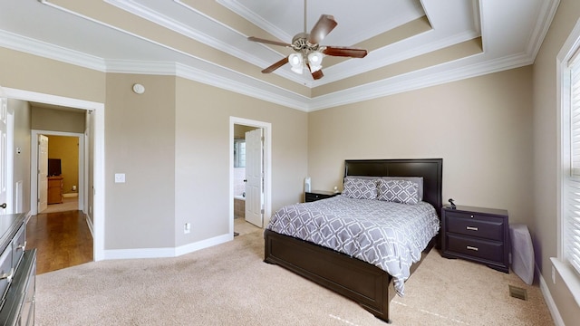 bedroom with a raised ceiling, light carpet, crown molding, and ensuite bath