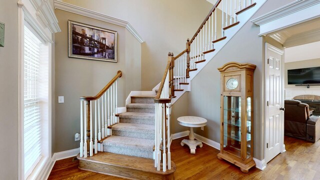 stairs with crown molding, a fireplace, and hardwood / wood-style floors