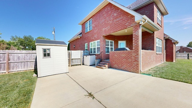 back of house with a patio, a yard, and a storage shed