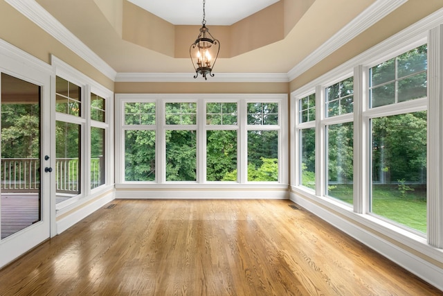 unfurnished sunroom featuring an inviting chandelier, a raised ceiling, and a healthy amount of sunlight