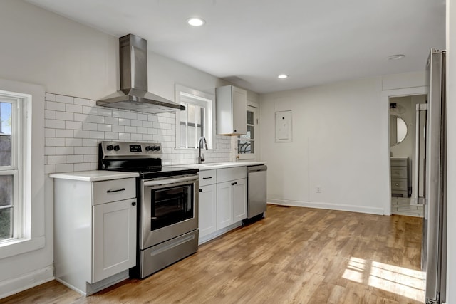 kitchen featuring light hardwood / wood-style flooring, a wealth of natural light, stainless steel appliances, and wall chimney range hood