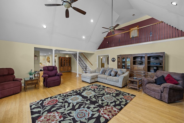 living room featuring high vaulted ceiling, light hardwood / wood-style floors, ceiling fan, and decorative columns