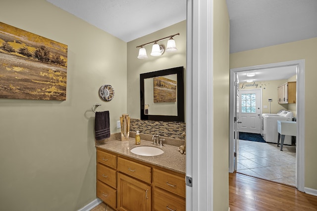 bathroom featuring tile flooring, vanity, tasteful backsplash, and washer and clothes dryer